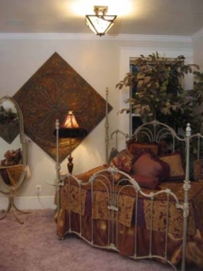 Idea House: A combination of an Old World Bed & Bedding, artifact tins, and a Victorian fairy wreath surround the bed. Window featuers an iron pine bough sculpture & iron shutters. Painted desk with contemporary lamp and hand- painted parsons chairs give this room an eclectic, fun and "Shabby Chic" look.