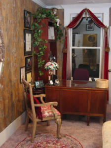 Old world with heavy wall textures and faux finishes. Silk window treatment with Art Deco scarf holders. Toile chair, Damask sofa with fringe, large, round, sculpted mirror, area rug, pillows and lamps make a statement in this small room.